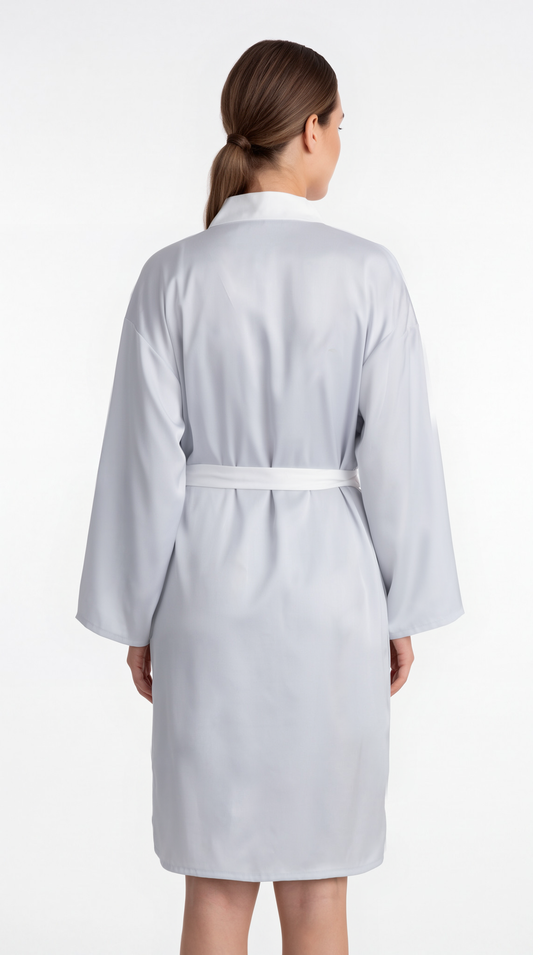 A woman viewed from the back wearing a light gray bathrobe with a white collar and a matching waist tie, set against a plain white studio background.