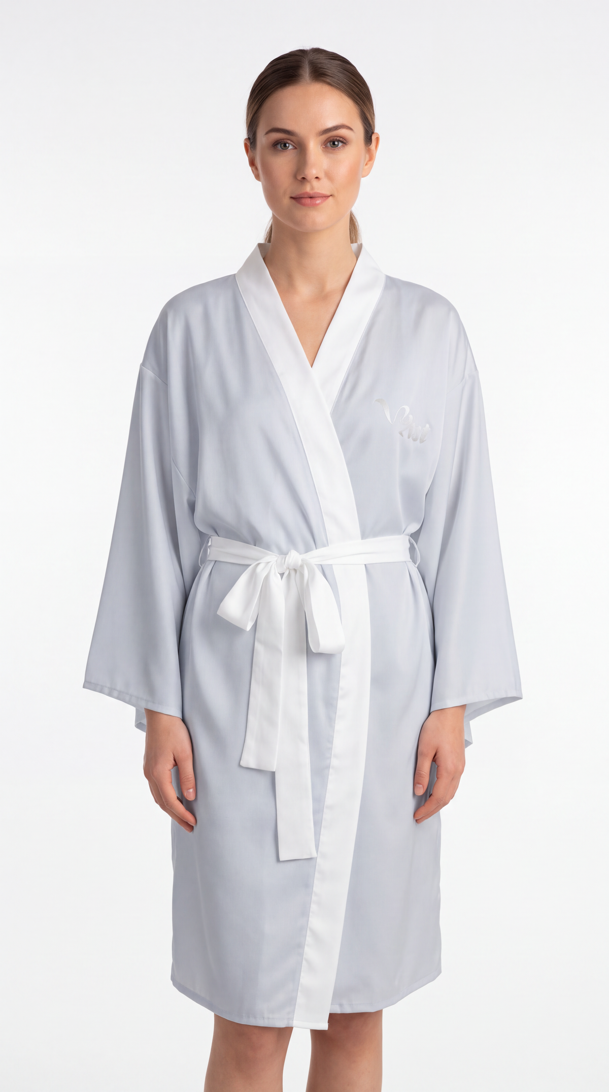 A woman modeling a light blue bathrobe with a white collar, front trim, belt, and tie, photographed against a plain white studio background.