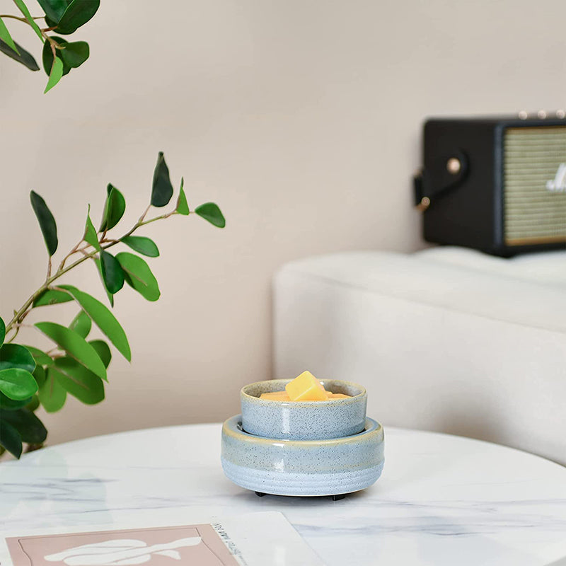 VibraMist River Stone fragrance warmer with yellow wax melts on a white marble-look table beside leafy greenery.