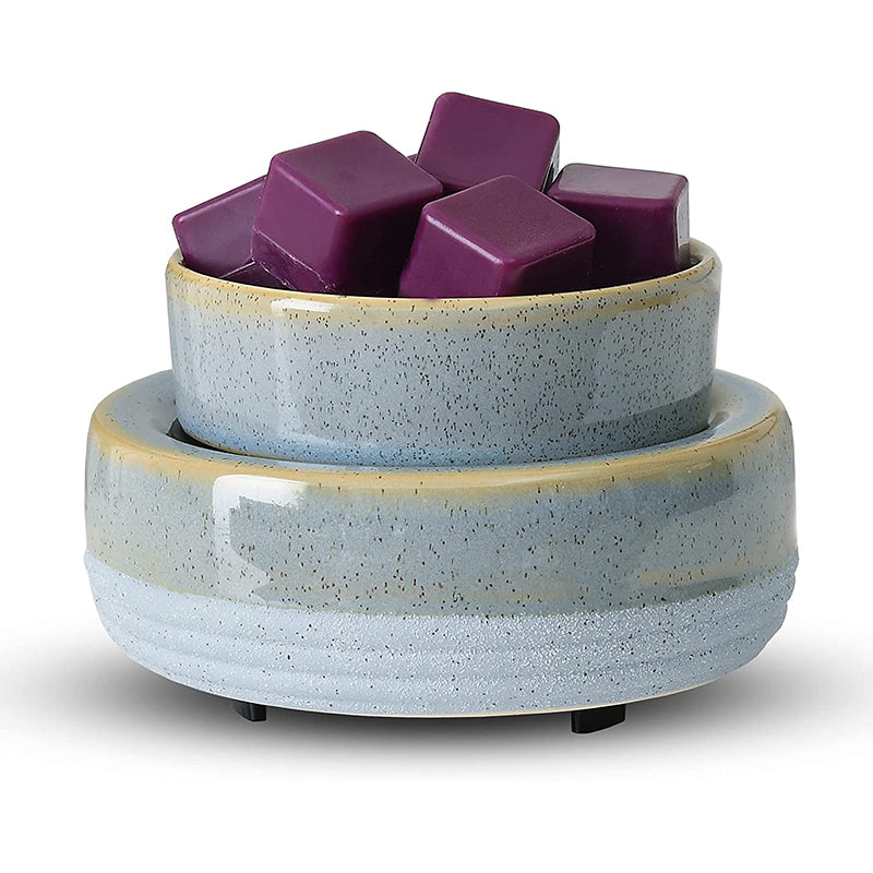 Close-up of the VibraMist River Stone fragrance warmer, showing its rounded blue-gray base, speckled glaze, and dish of purple wax melts.