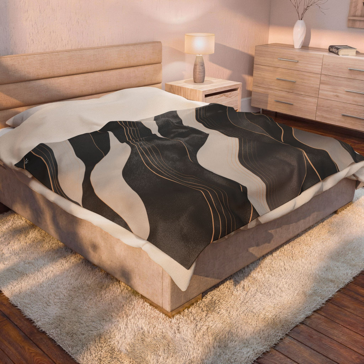 A bed in a modern bedroom setting, featuring a dark charcoal gray and beige abstract wavy patterned throw blanket with thin gold lines.